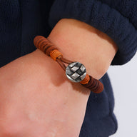 Bracelet homme en cuir marron avec bouton métal argenté à motif géométrique.