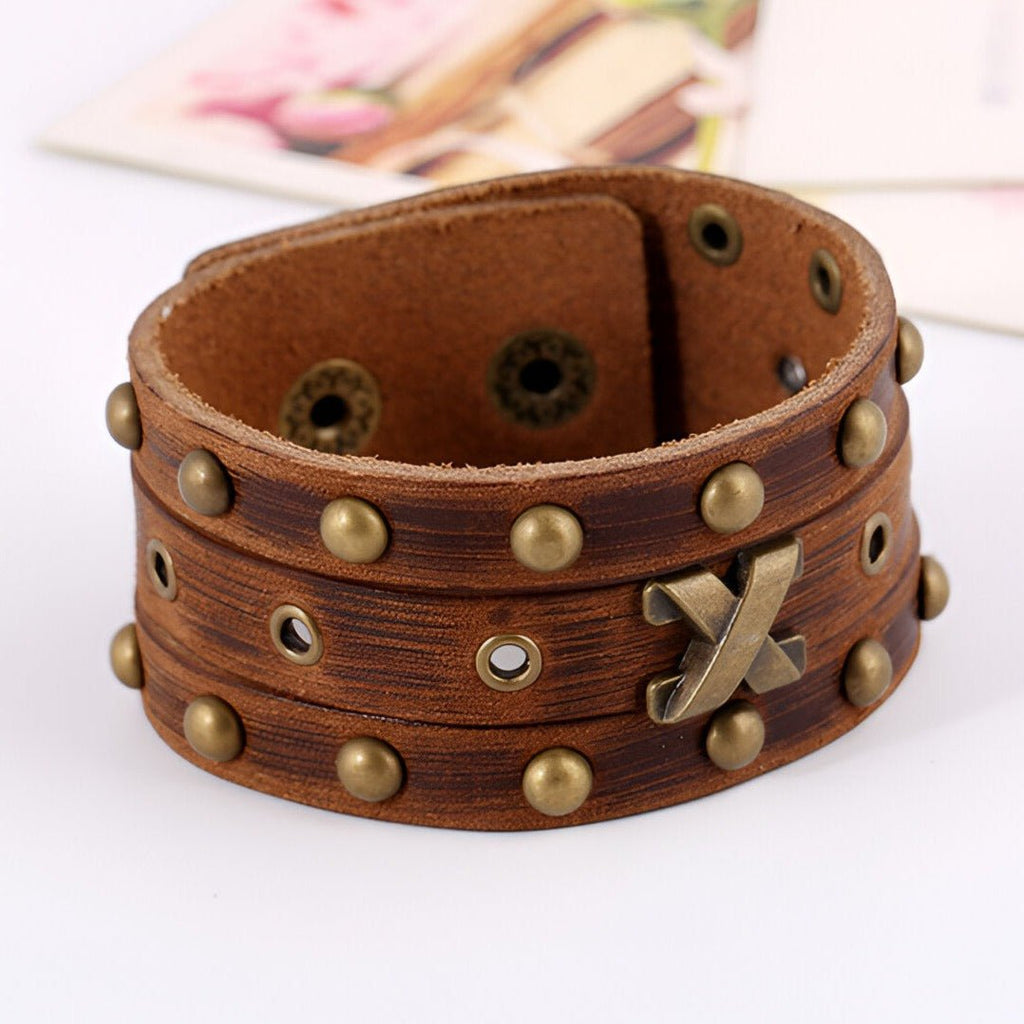 Bracelet en cuir marron large pour homme avec rivets et détail métallique croisé.