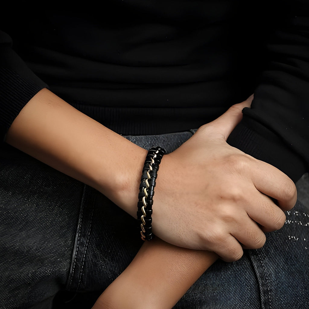 Bracelet en cuir noir avec détails ondulés et fermoir argenté porté au poignet.