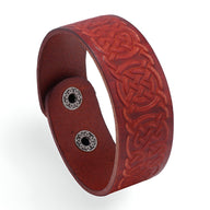 Bracelet en cuir marron avec motifs gaufrés entrelacés et fermoir à boutons-pression métalliques.