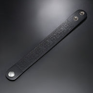 Bracelet en cuir noir pour homme avec motifs gaufrés et fermoir à pression métallique argenté.