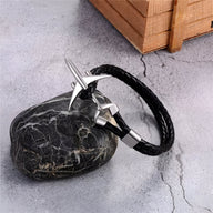 Bracelet noir en cuir tressé avec avion en acier inoxydable brillant et fermoir élégant.