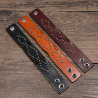 Trois bracelets en cuir clouté style western, couleurs noir, orange et café, fermoirs pression métalliques.