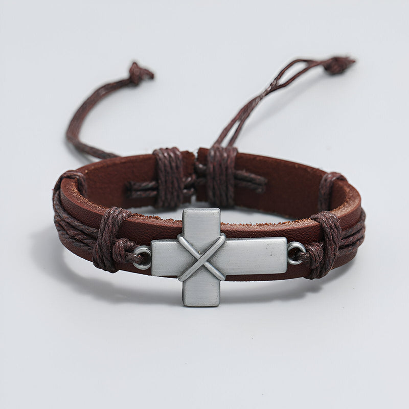 Bracelet homme en cuir marron avec croix chrétienne métallique centrale et lanières ajustables.