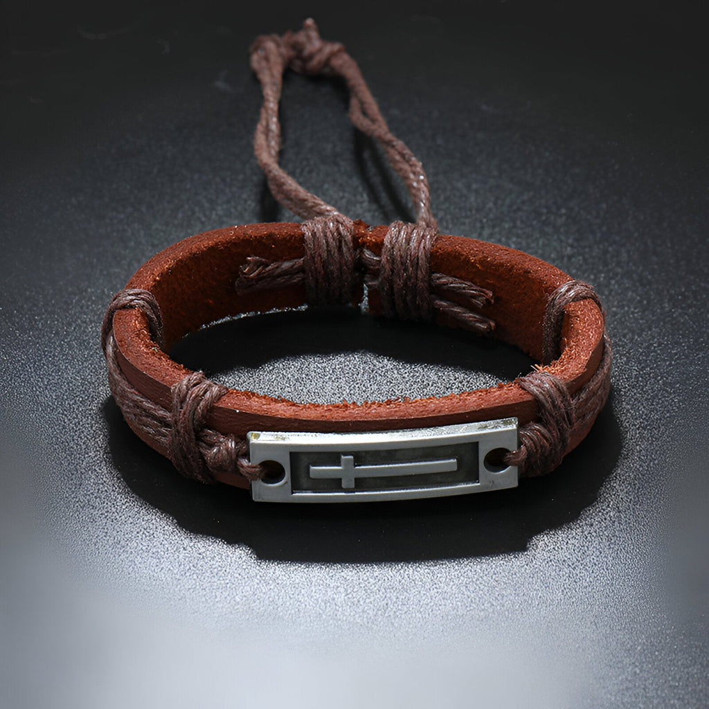 Bracelet homme en cuir marron tressé avec plaque en métal et croix chrétienne gravée.