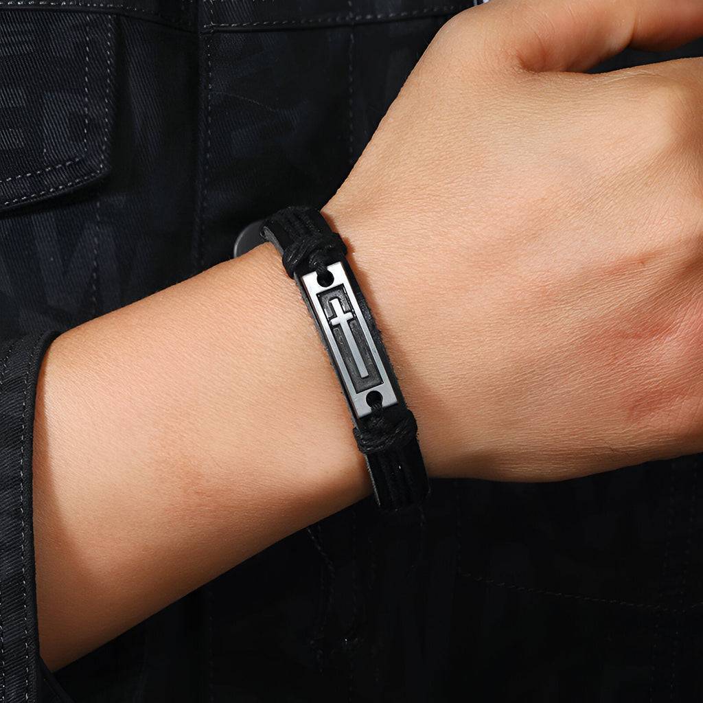 Bracelet en cuir noir avec plaque métallique argentée ornée d'une croix chrétienne, style masculin.