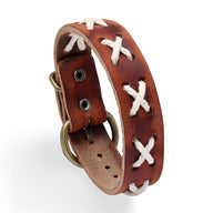 Bracelet en cuir marron avec croix tressées blanches et boucle métallique antique.