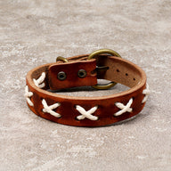 Bracelet en cuir marron avec croix blanches tressées et boucle en métal antique.