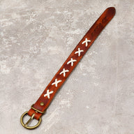 Bracelet en cuir marron avec croix blanches tressées et boucle métal doré.
