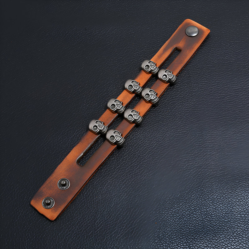 Bracelet en cuir marron double tour avec six têtes de mort en métal argenté et fermeture pression.