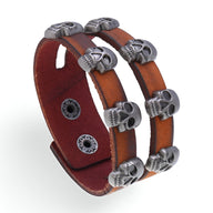 Bracelet en cuir marron double tour avec têtes de mort en métal argenté, fermoir à pression.