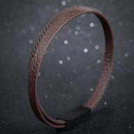 Bracelet double-rang en cuir marron avec fermoir noir mat et texture grainée.