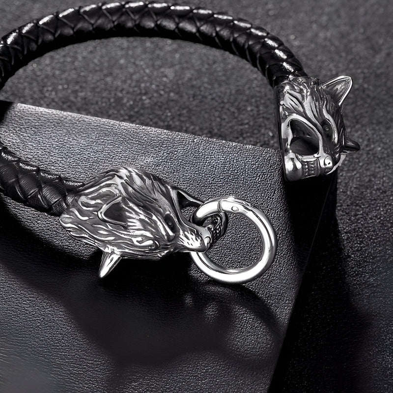 Bracelet noir en cuir tressé avec fermoir double tête de loup argentée, style masculin.
