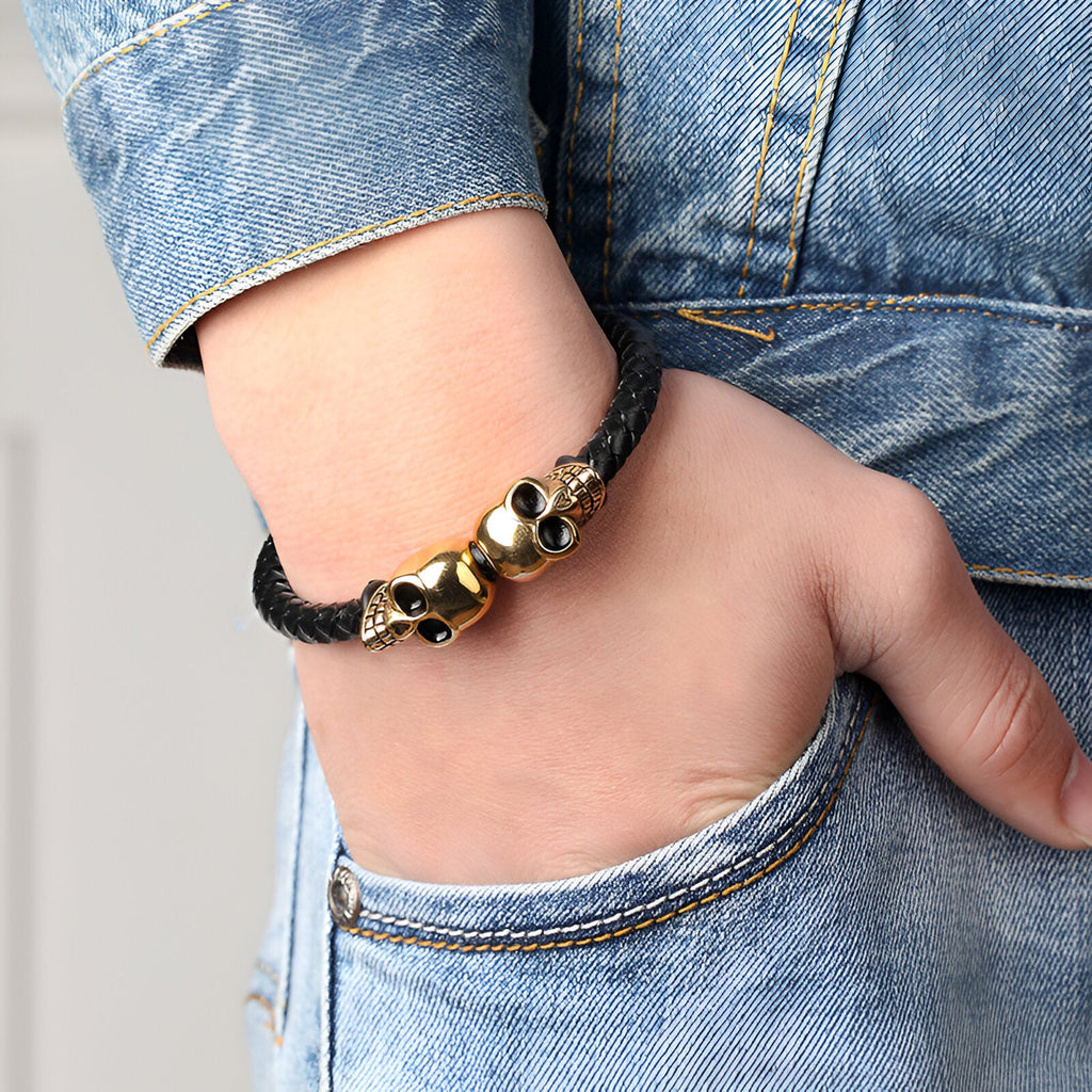 Bracelet en cuir noir avec deux têtes de mort dorées, style edgy et masculin.