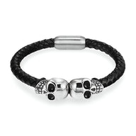 Bracelet en cuir noir tressé avec deux têtes de mort argentées en fermoir.