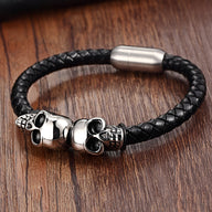 Bracelet en cuir noir tressé avec double têtes de mort argentées et fermoir magnétique argenté.