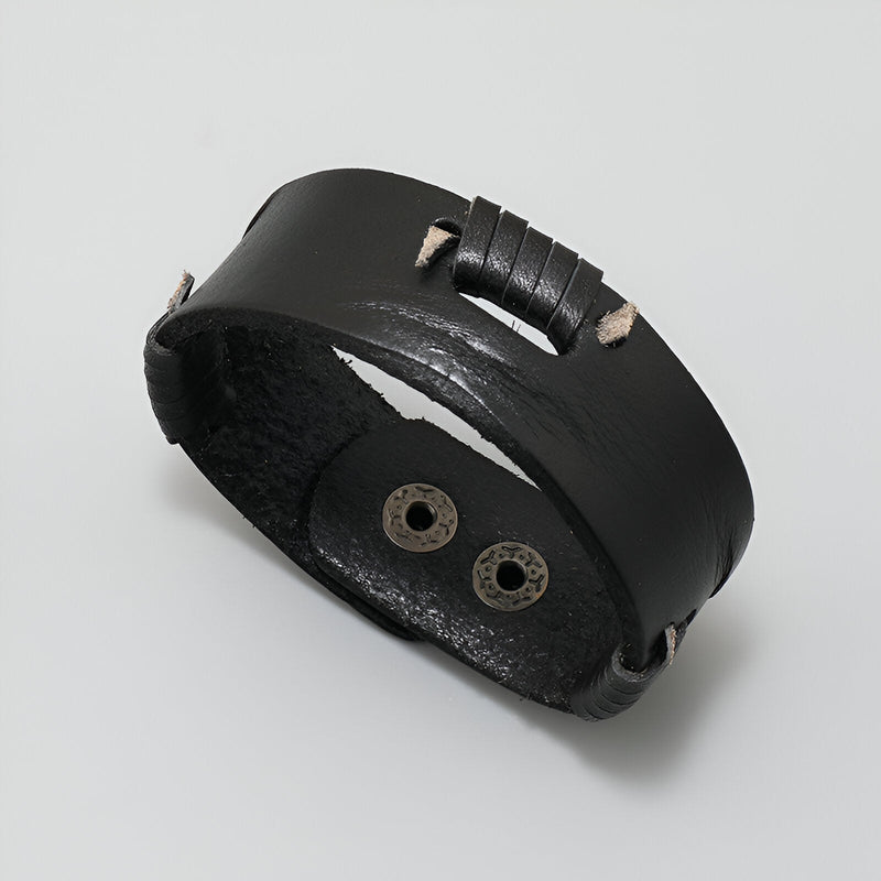 Bracelet en cuir noir effet usé, large, avec surpiqûres contrastées et fermeture à boutons pression.