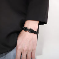 Bracelet noir en cuir avec motif infini en acier inoxydable, modèle Betis, porté au poignet.