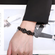 Bracelet homme noir en cuir tressé avec motif infini en acier inoxydable noir.