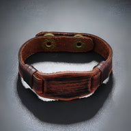 Bracelet large en cuir marron vieilli avec boutonnières en métal doré, style vintage masculin.