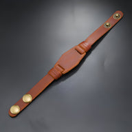 Bracelet large en cuir marron avec fermeture à boutons-pression dorés pour homme.