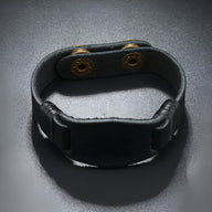 Bracelet large en cuir noir pour homme avec fermeture à boutons-pression dorés.