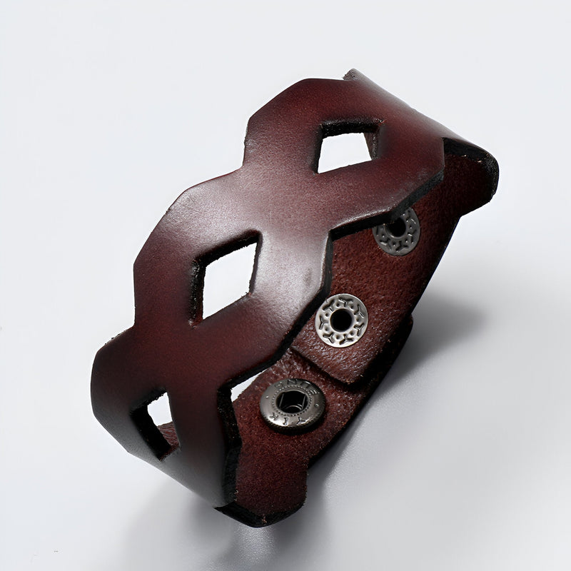 Bracelet large en cuir café avec découpes géométriques et fermeture à boutons-pression argentés.