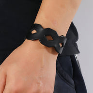 Bracelet large en cuir noir avec découpes géométriques en forme de losange, style masculin.
