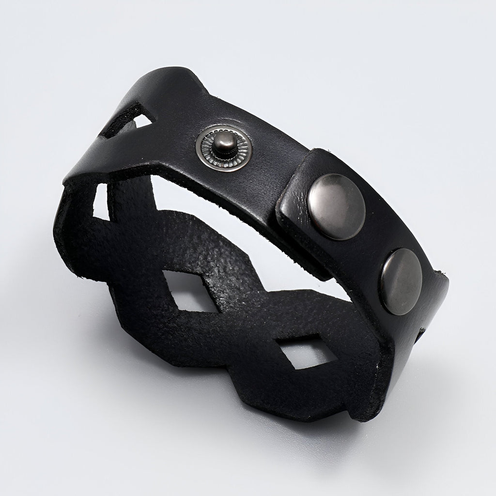 Bracelet large en cuir noir avec découpes géométriques et fermoir à boutons-pression en métal.