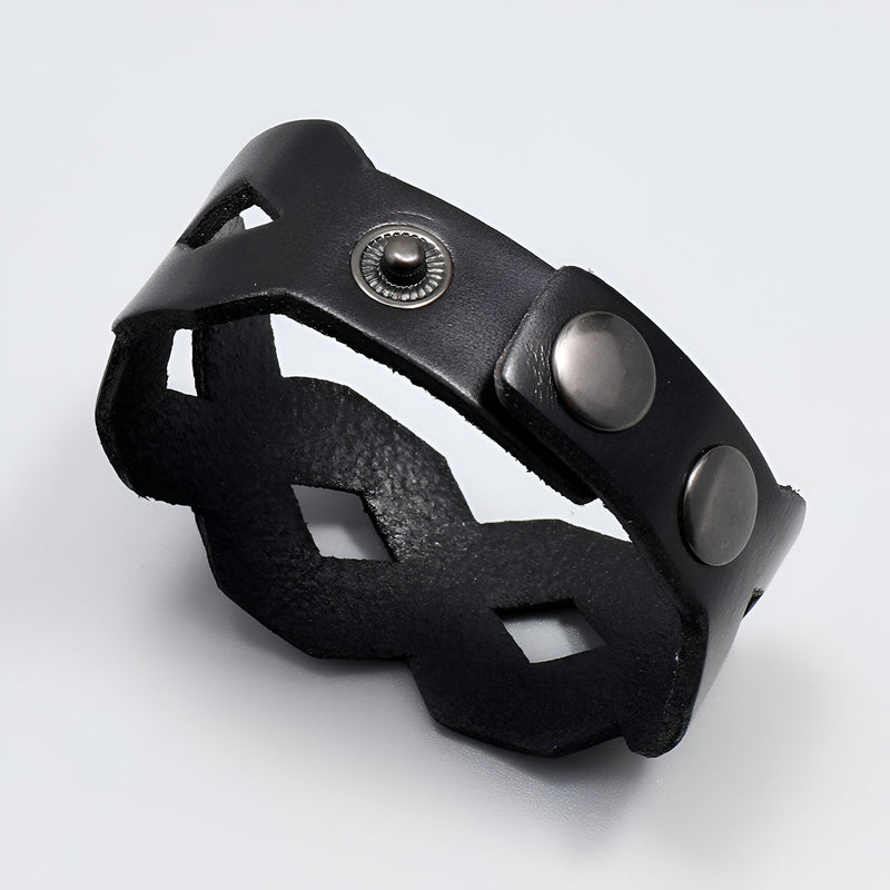 Bracelet large en cuir noir avec découpes géométriques et fermoir à boutons-pression en métal.
