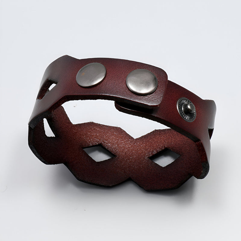 Bracelet large en cuir café avec formes géométriques et fermoir à boutons-pression métalliques.