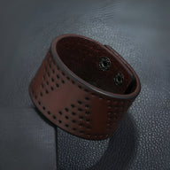 Bracelet manchette large en cuir café perforé à trous avec fermeture à boutons-pression métalliques.