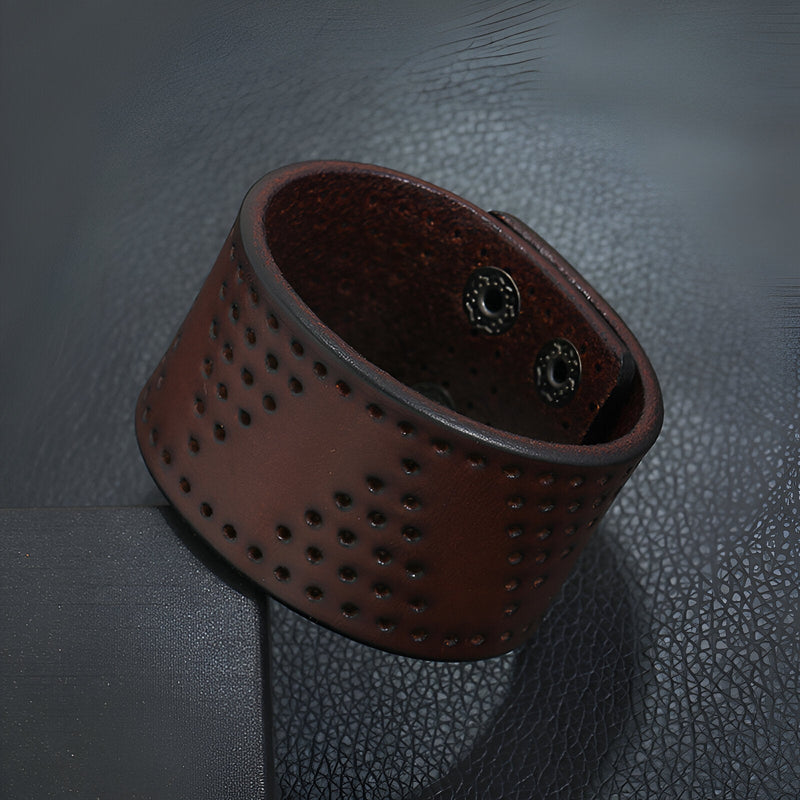 Bracelet manchette large en cuir café perforé à trous avec fermeture à boutons-pression métalliques.
