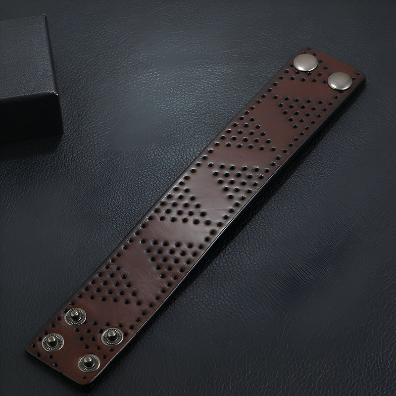 Bracelet large en cuir café avec motif de trous géométriques et fermoirs à pression métalliques.