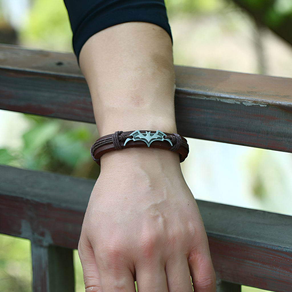 Bracelet en cuir marron avec logo Batman argenté, style masculin et robuste.