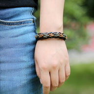 Bracelet en cuir marron tressé et torsadé, style unisexe, porté au poignet.