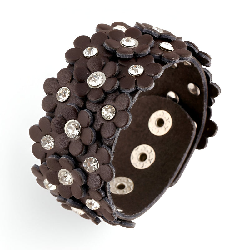 Bracelet manchette en cuir café orné de fleurs en relief avec strass brillants et fermeture à boutons-pression.
