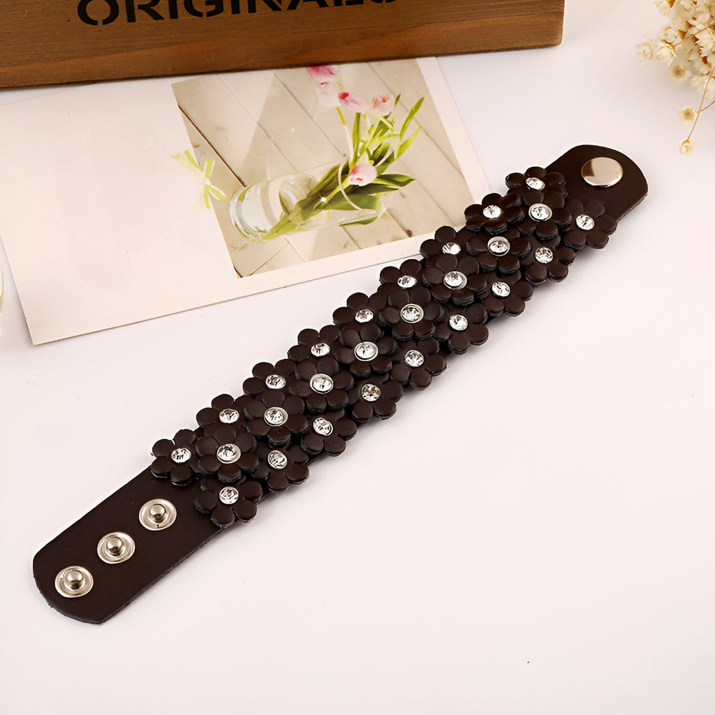 Bracelet manchette en cuir café orné de fleurs ajourées et de perles blanches, fermoir à boutons-pression.