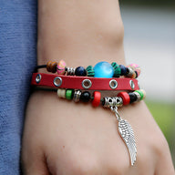 Bracelet en cuir rouge à double tour avec perles multicolores et pendentif aile argenté.