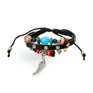 Bracelet en cuir noir avec perles colorées et pendentif aile en métal argenté ajustable.