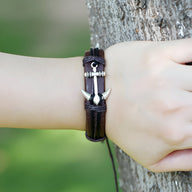 Bracelet en cuir marron avec motif ancre marine en métal argenté et fermeture réglable.
