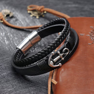 Bracelet noir en cuir tressé avec motif ancre marine en métal argenté et fermoir aimanté en acier inoxydable.