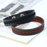 Bracelet en cuir noir avec motif de petits cœurs embossés, fermeture à bouton-pression.