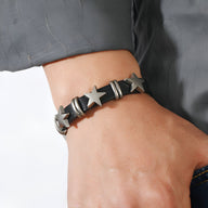 Bracelet en cuir noir pour homme avec étoiles métalliques argentées et détails en anneaux.