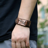 Bracelet en cuir café avec motif hache en métal, ajustable, style masculin et robuste.