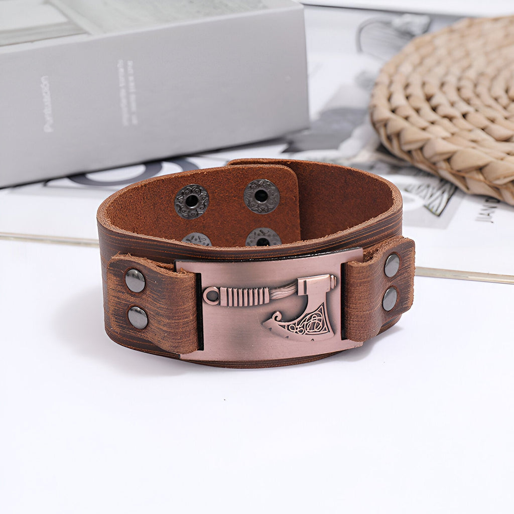 Bracelet en cuir marron avec motif hache en métal cuivré et fermeture à pression ajustable.