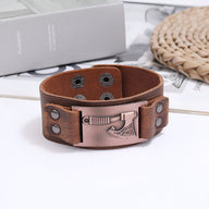 Bracelet en cuir marron avec motif hache en métal cuivré et fermeture à pression ajustable.