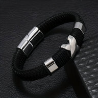 Bracelet en cuir noir tressé avec motif petite croix argentée et fermoir magnétique en métal brillant.