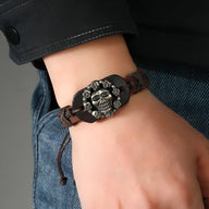 Bracelet en cuir marron tressé avec motif tête de mort en métal argenté sur poignet homme.