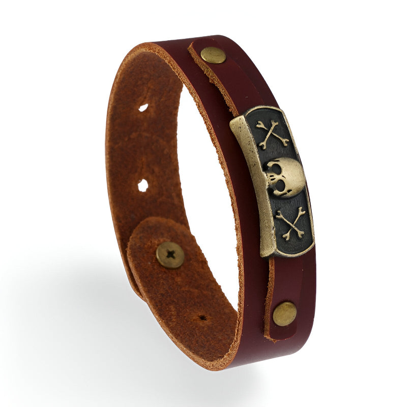 Bracelet en cuir marron avec motif tête de mort et os croisés en métal argenté, fermeture à bouton-pression.
